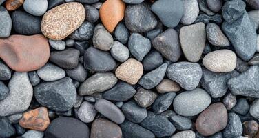 Collection of smooth river rocks in varying shades on a natural surface photo
