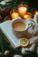 Cozy winter scene with a cup of lemon tea, a book, and a candle on a knitted blanket photo