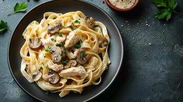 Creamy fettuccine Alfredo with mushrooms and chicken on a dark rustic table photo