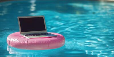 A modern laptop rests on a pink pool float, bobbing in clear water, symbolizing the blend of work and relaxation for the workaholic seeking balance in their busy life and enjoyment photo