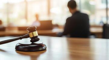 A gavel is prominently resting on a table, while a glimpse of courtroom proceedings can be seen in the background photo