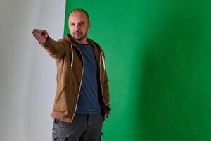 Middle aged bald man demonstrating composition techniques with hand gestures against a green studio backdrop. photo