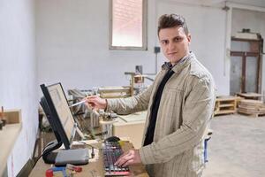 Operator Entering Coordinates on Computer for CNC Machine to Precisely Cut Wooden Pieces photo