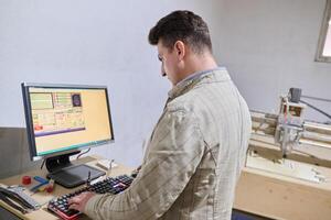 Operator Entering Coordinates on Computer for CNC Machine to Precisely Cut Wooden Pieces photo