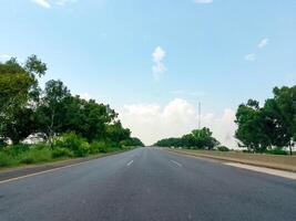 Highway road side view with green trees and blue sky photo
