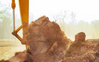 Closeup bucket of backhoe digging the soil at construction site. Crawler excavator digging on demolition site. Excavating machine. Earth moving equipment. Excavation vehicle. Construction business. photo