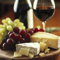 Arrangement of cheese, grapes, and wine on a wooden board, ideal for gourmet dining and culinary presentations. photo