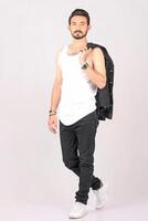 Portrait of a young stylish male model in black jeans jacket and pant with smile full height and sitting studio shots photo