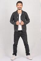 Portrait of a young stylish male model in black jeans jacket and pant with smile full height and sitting studio shots photo