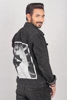 Portrait of a young stylish male model in black jeans jacket and pant with smile full height and sitting studio shots photo