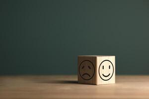 A smiling face on bright side and sad face on dark side of wooden block. Concept business for satisfaction assessment and mental health concepts for positive thinking and emotional states. photo