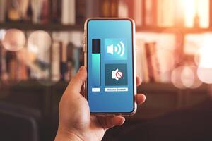 Close-up view of hand turning down the volume of smartphone in silent or mute mode activated. photo