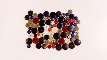 Buttons of various colors and shapes scattered on a white background. photo