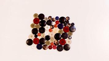 Buttons of various colors and shapes scattered on a white background. photo