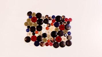 Buttons of various colors and shapes scattered on a white background. photo