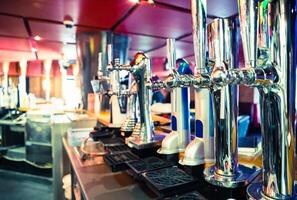 man bartender hand at beer tap pouring beer in glass in bar or pub photo