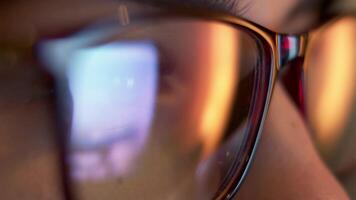 Close-up of a developer in glasses intensely working on a computer. Reflections of code and analytics in the glasses highlight expertise in cybersecurity and software development video