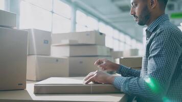Young man experienced shipping manager checking parcel tracking post service store assistant in warehouse logistics transportation holding cargo delivery order shipment online store shelf video