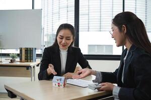 Real Estate Agents Discussing Property Sale with Model House in Office Setting photo