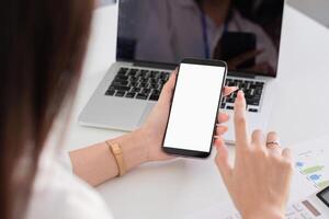 Young Accountant Using Smartphone While Working on Laptop in Modern Office Environment photo