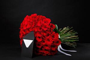 101 Bouquet of red roses with a black envelope for a logo, on a black studio background, spring is coming, 8 March photo