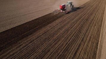 A tractor on the field plows the land, a combine harvester, a view from a drone photo