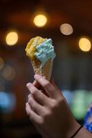 Close up hand of a person holding a cone of ice cream with blurred background photo