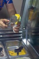 Close up hand of a person scooping ice cream in to a cone with blurred background photo
