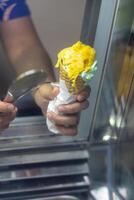 Close up hand of a person scooping ice cream in to a cone with blurred background photo