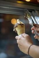 Close up hand of a person scooping ice cream in to a cone with blurred background photo