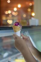Close up hand of a person holding a cone of ice cream with blurred background photo