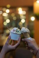 Close up hand of a person holding a cup and a cone of ice cream with blurred background photo