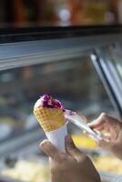Close up hand of a person scooping ice cream in to a cone with blurred background photo