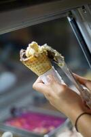 Close up hand of a person scooping ice cream in to a cone with blurred background photo