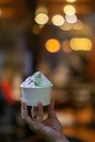 Close up hand of a person holding a cup of ice cream with blurred background photo