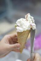 Close up hand of a person scooping ice cream in to a cone with blurred background photo