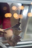Close up hand of a person scooping ice cream in to a cone with blurred background photo
