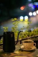 Cup of coffee and teapot on the table with blurred background photo