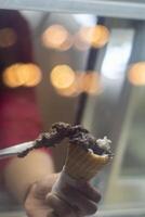 Close up hand of a person scooping ice cream in to a cone with blurred background photo
