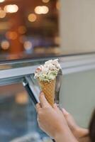 Close up hand of a person holding a cone of ice cream with blurred background photo