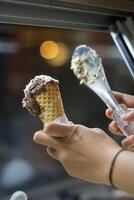 Close up hand of a person holding a cone of ice cream with blurred background photo