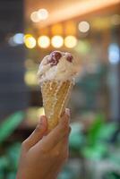 Close up hand of a person holding a cone of ice cream with blurred background photo