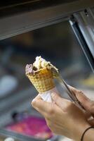 Close up hand of a person scooping ice cream in to a cone with blurred background photo