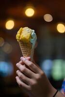 Close up hand of a person holding a cone of ice cream with blurred background photo