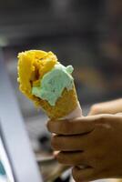 Close up hand of a person holding a cone of ice cream with blurred background photo