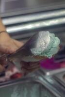 Close up hand of a person scooping ice cream in to a cone with blurred background photo