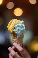 Close up hand of a person holding a cone of ice cream with blurred background photo
