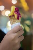 Close up hand of a person holding an ice cream cone with blurred background photo