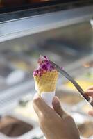 Close up hand of a person scooping ice cream in to a cone with blurred background photo