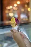 Close up hand of a person holding ice cream cone with blurred background photo